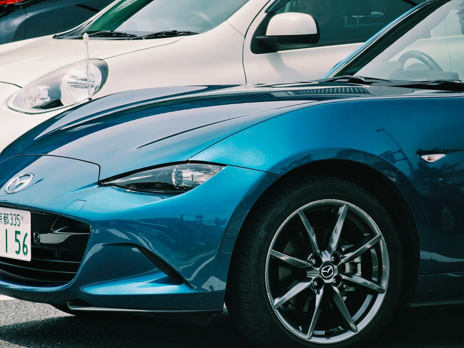 Close-up of a blue Mazda MX-5 headlight and front wheel