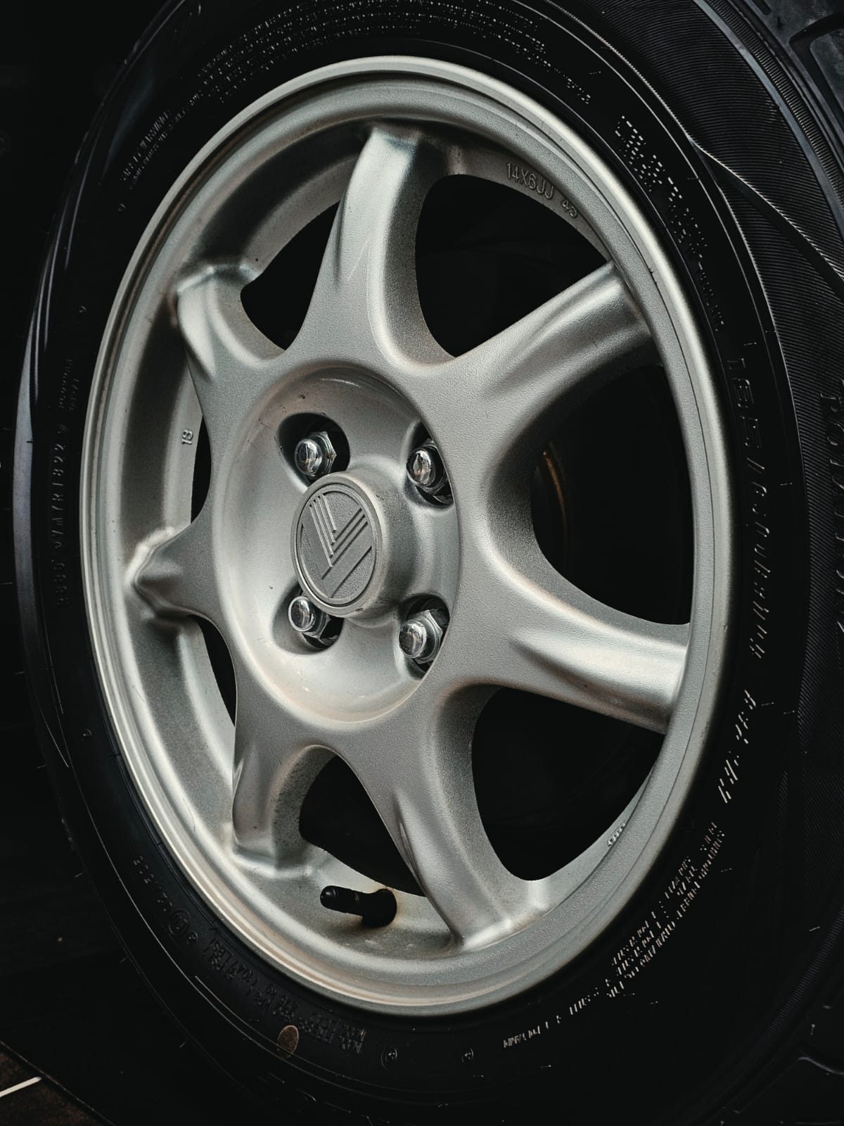 Close-up of a silver six-spoke wheel on the museum floor