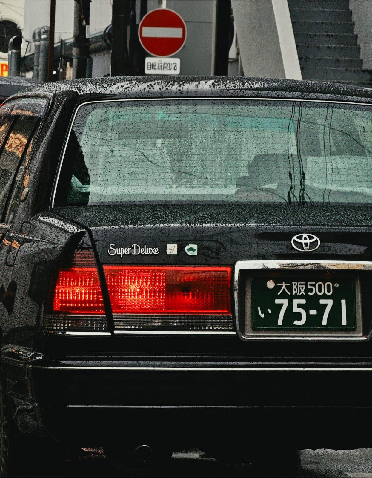 Black Toyota Crown Super Deluxe rear in the rain