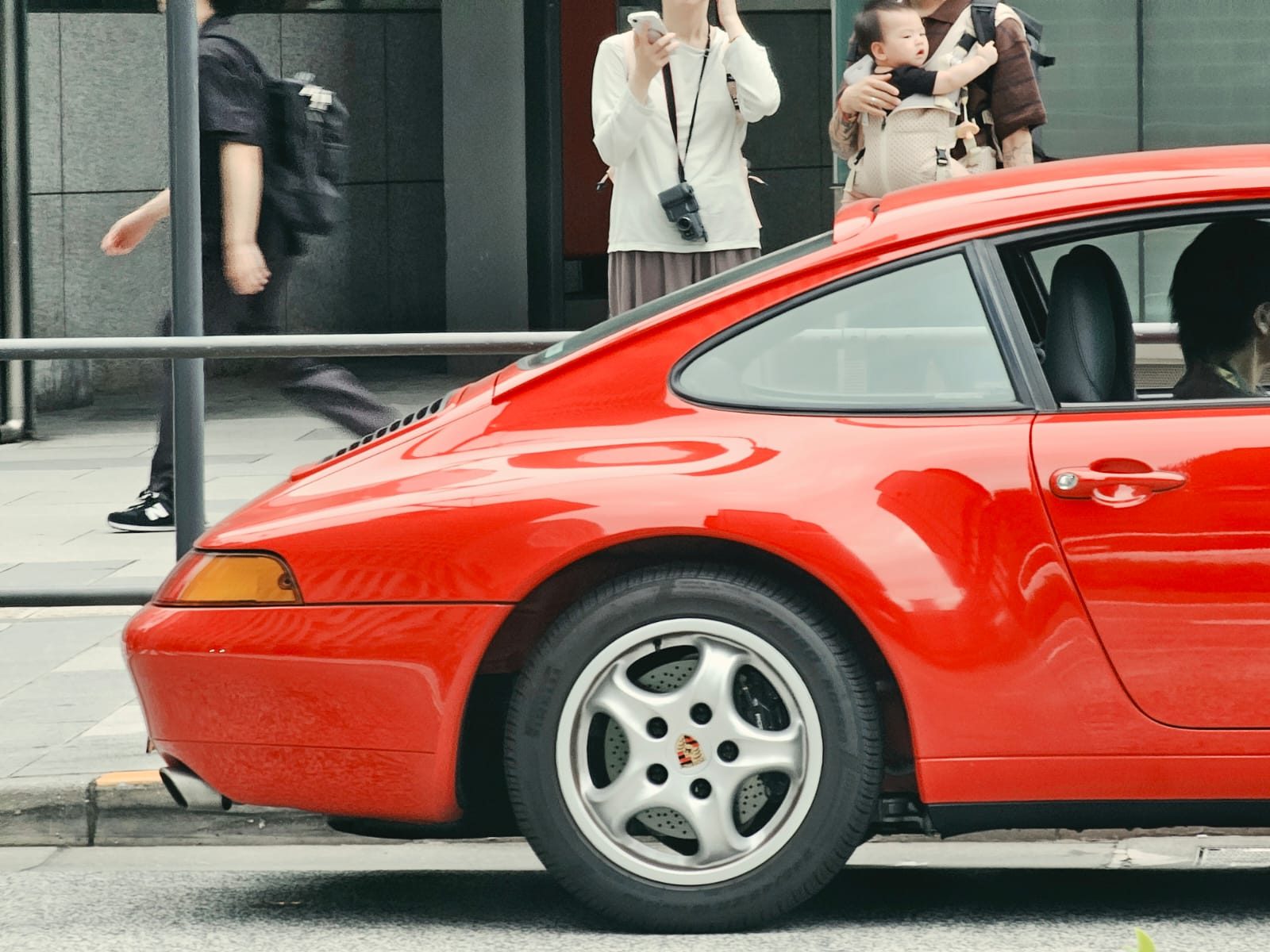 Red Porsche 911 993 profile with onlookers in the background