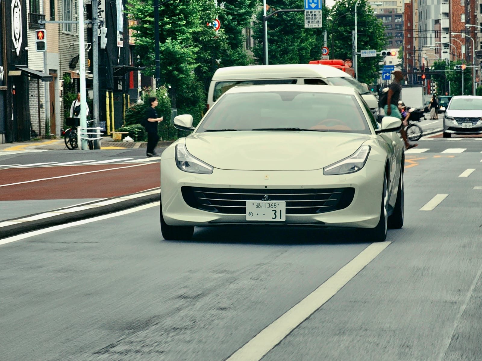 Cream Ferrari GTC4Lusso driving toward camera in Tokyo traffic