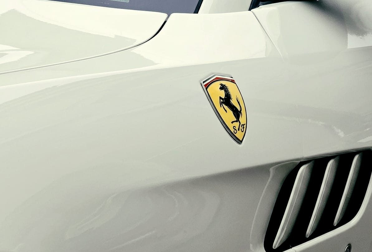 Close-up of a Ferrari badge on a cream body panel