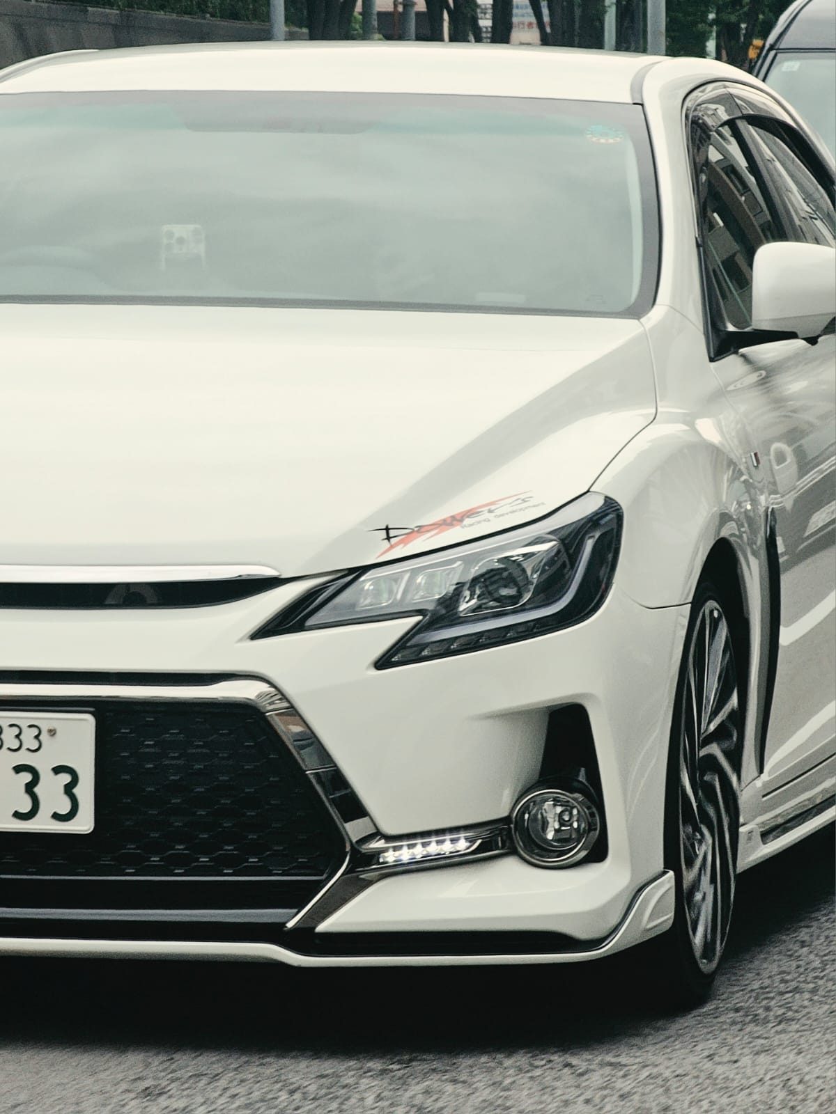 Close-up of a white Toyota Mark X front end with TRD badge