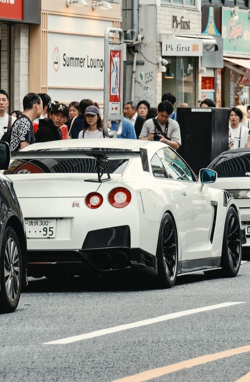 White Nissan GT-R R35 rear view on a crowded Tokyo street