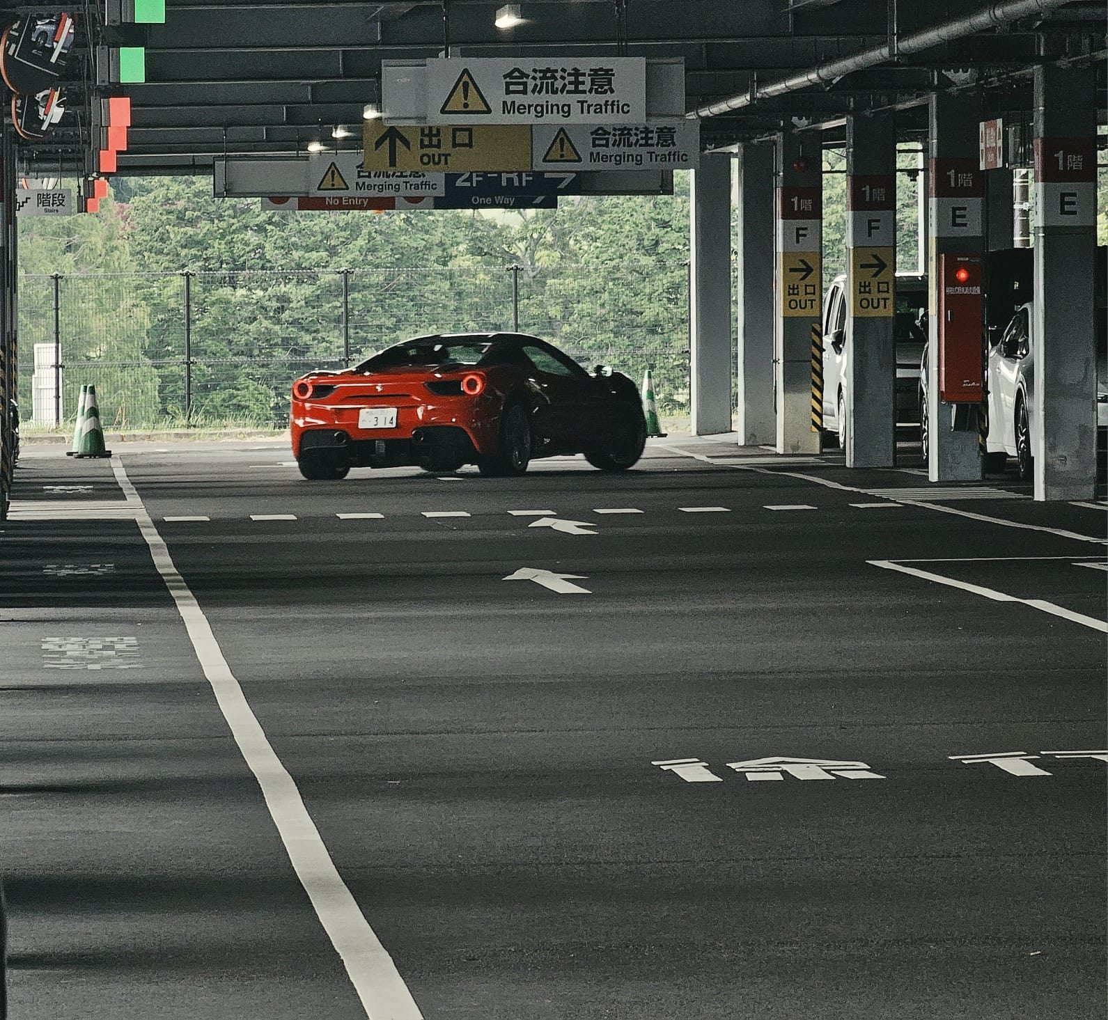 Red Ferrari 488 driving through a multi-level parking garage