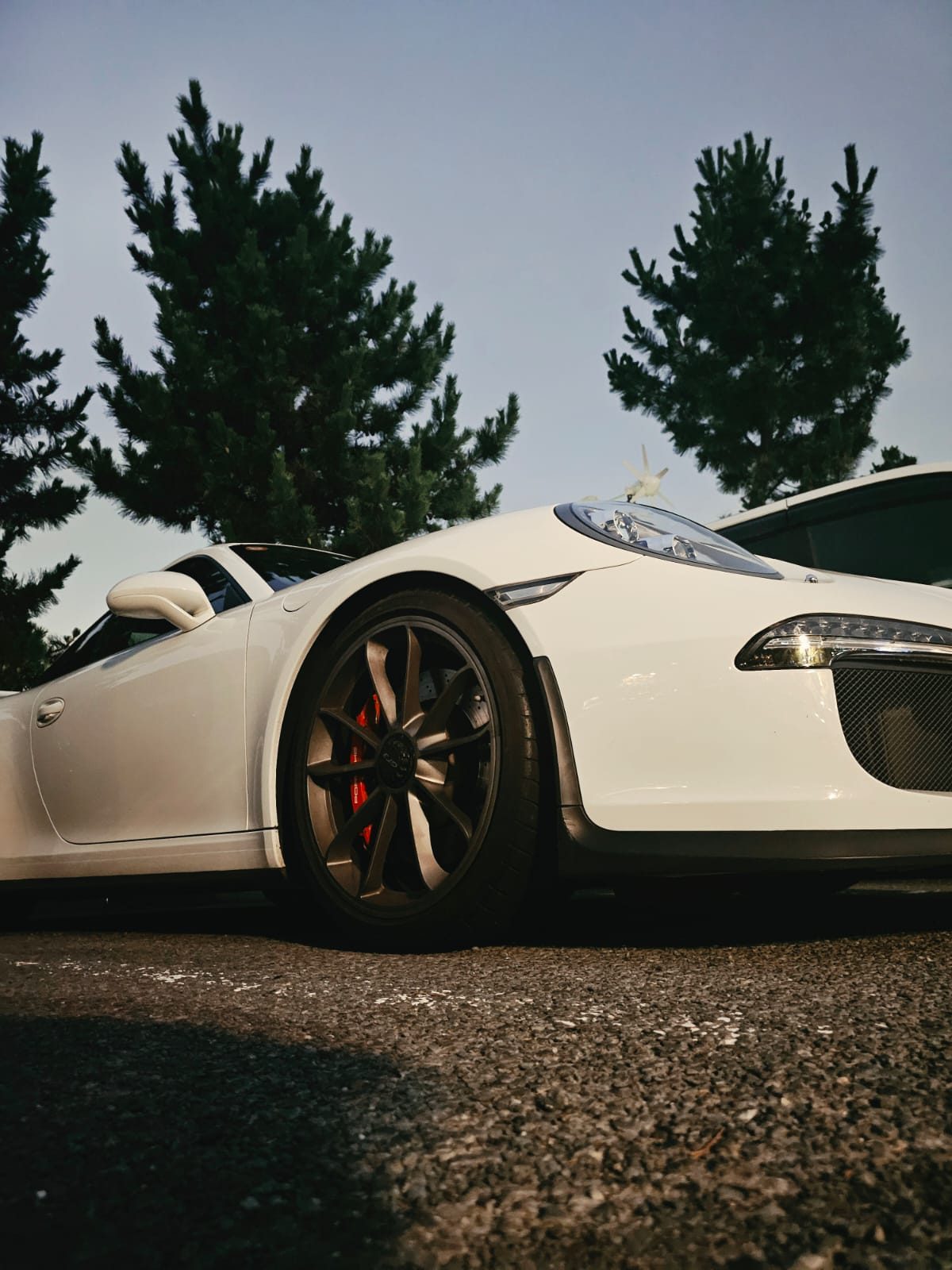 Close-up of a white Porsche's wheel and headlight