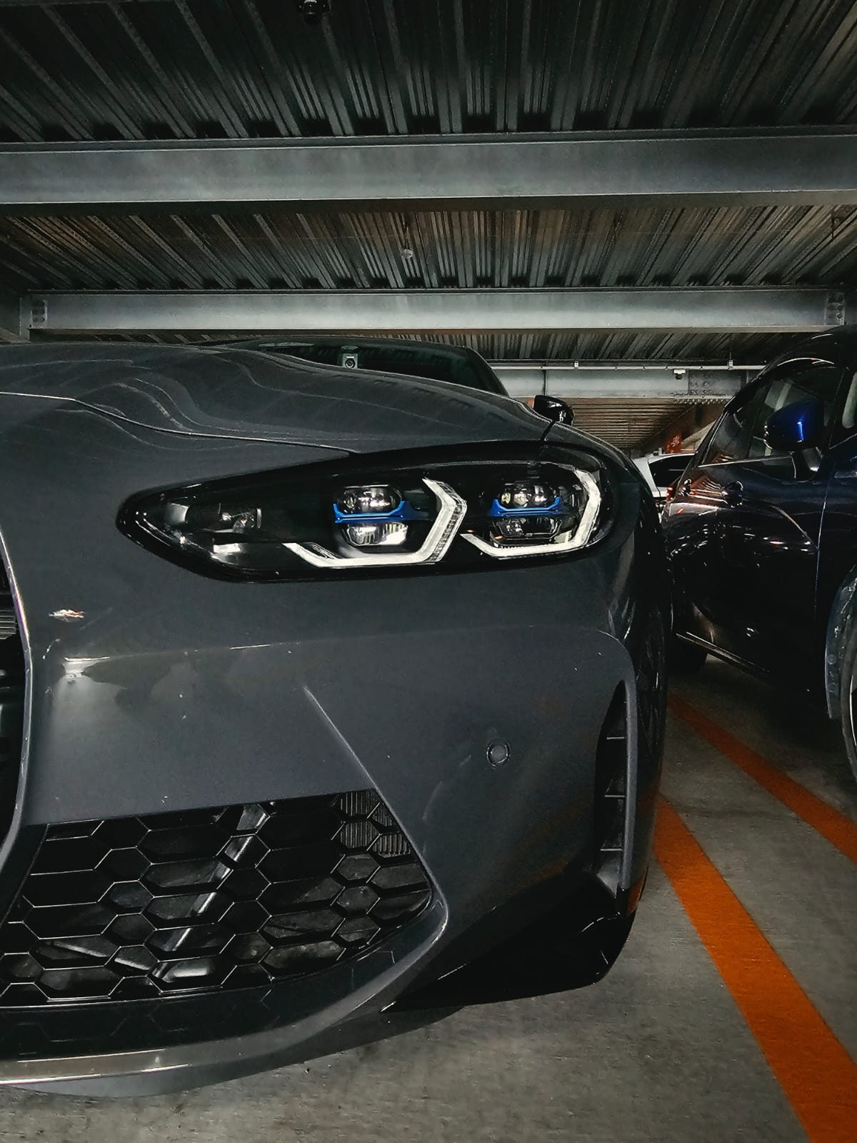 Close-up of a grey BMW M2 headlight in a parking garage