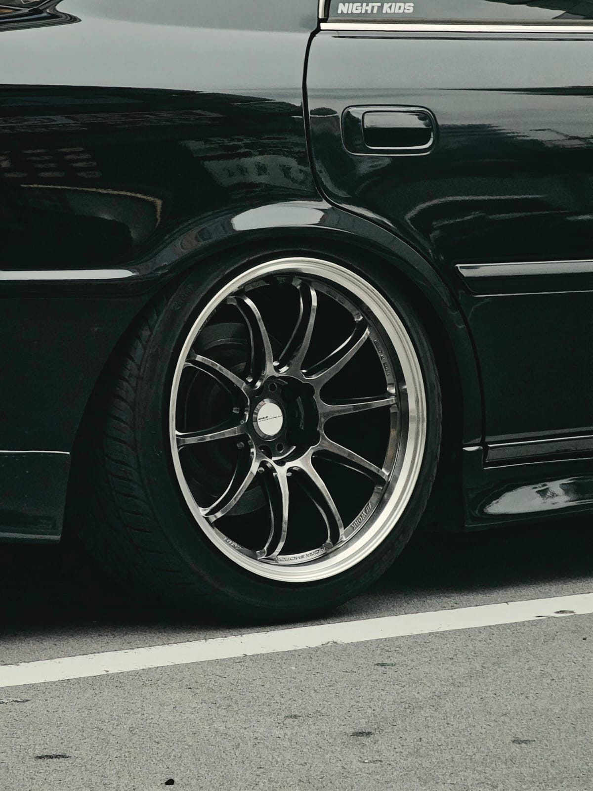 Close-up of the Toyota Chaser's wheel with a Night Kids window sticker