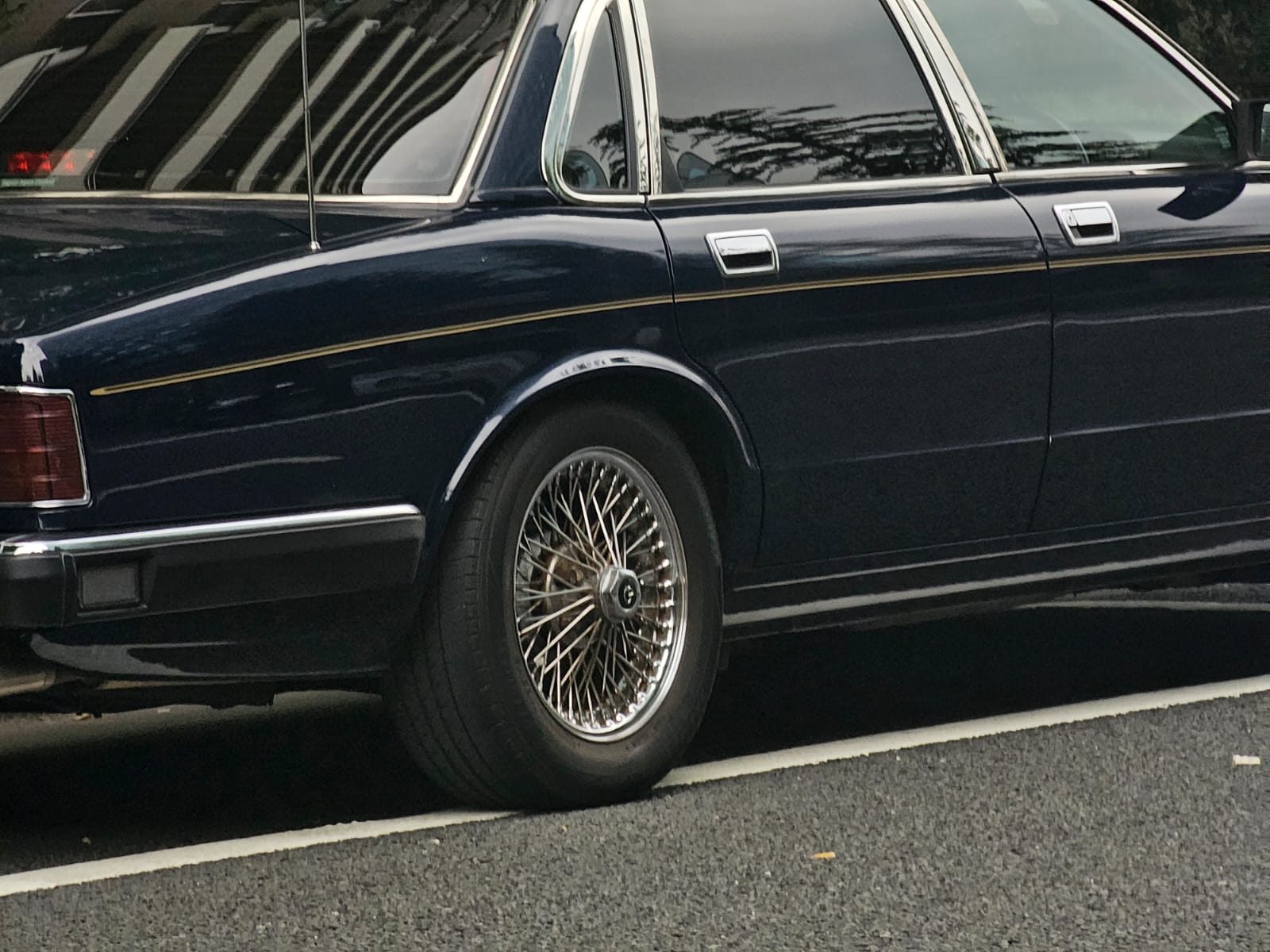 Close-up of a navy Jaguar XJ with wire wheels