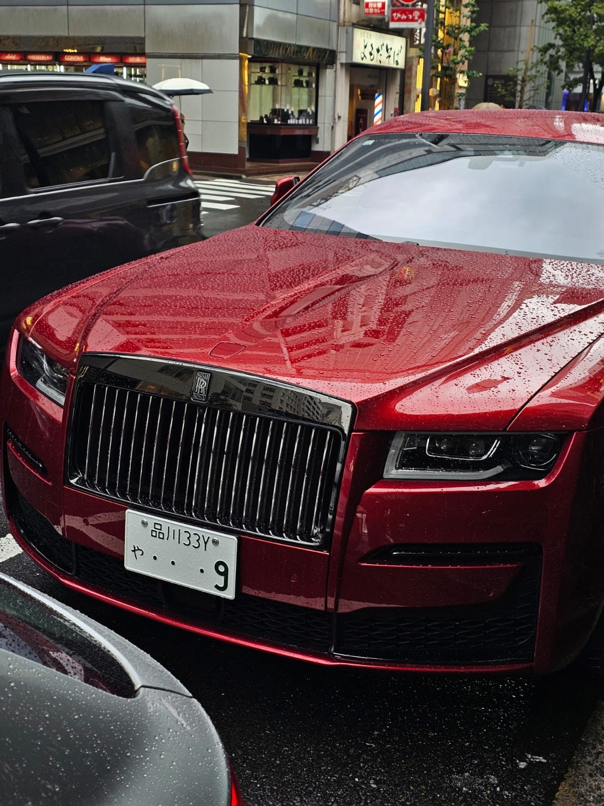 Red Rolls-Royce Ghost grille and headlight close up in the rain