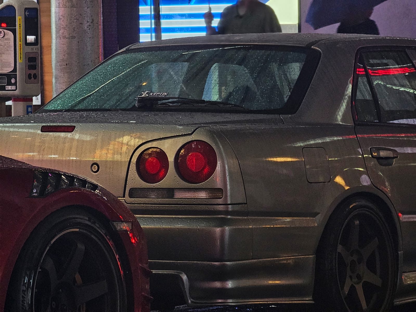 Close-up of a silver Nissan Skyline R34's round tail lights at night
