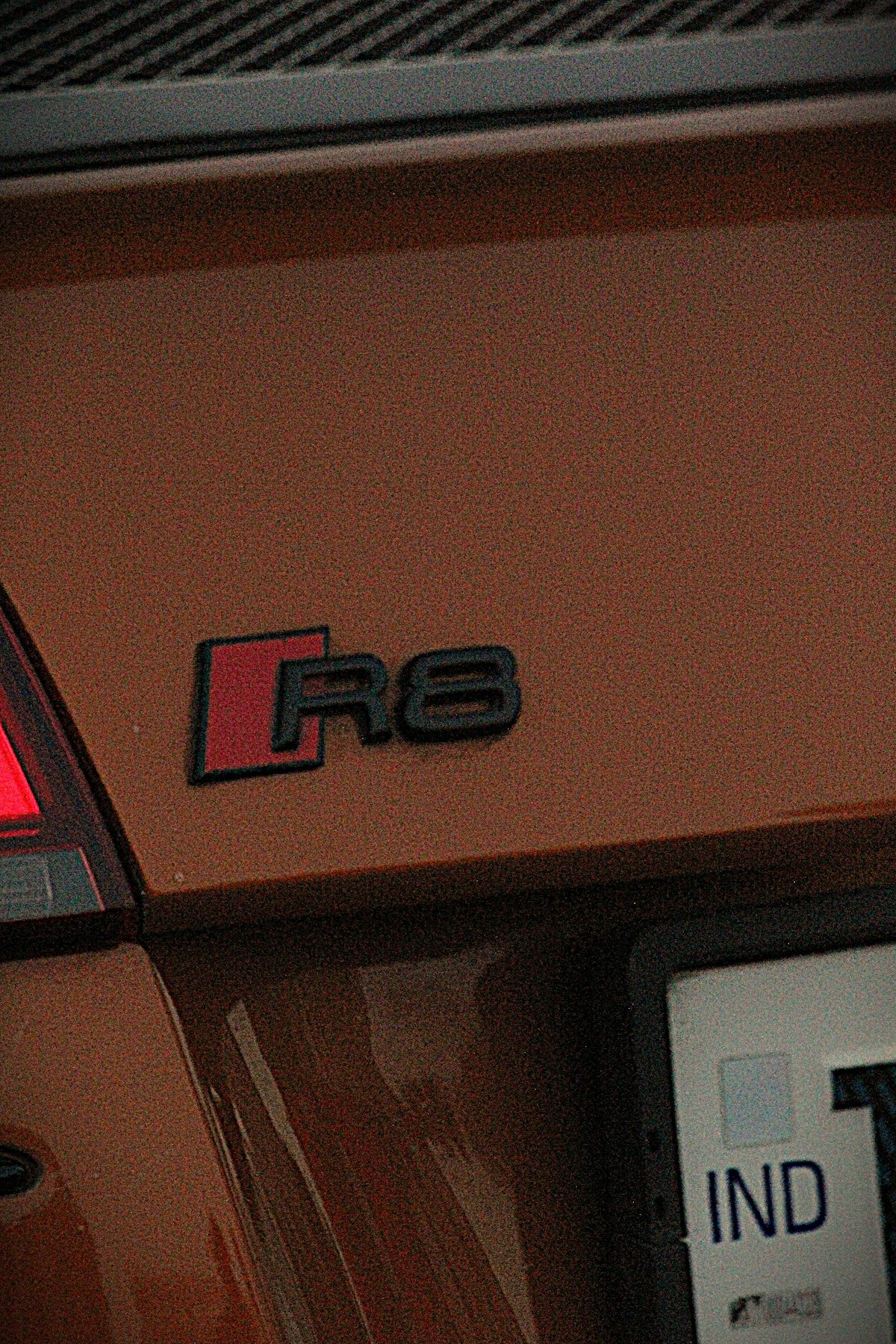 Grainy close-up of the R8 badge on the Audi's rear panel at night