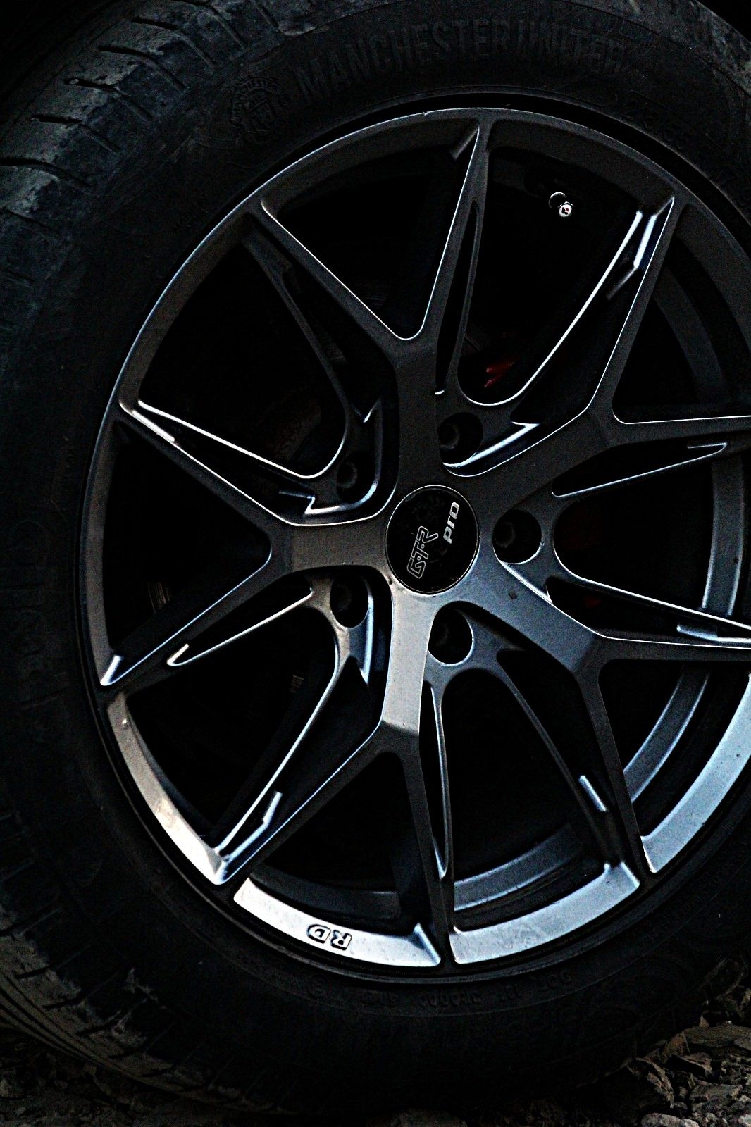 Close-up of a modified grey alloy wheel with a red brake caliper