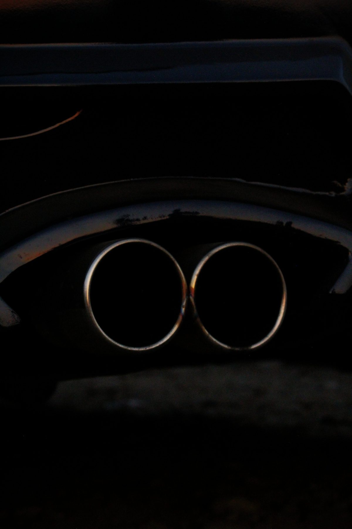 Close-up of chrome dual exhaust tips on a modified car at dusk