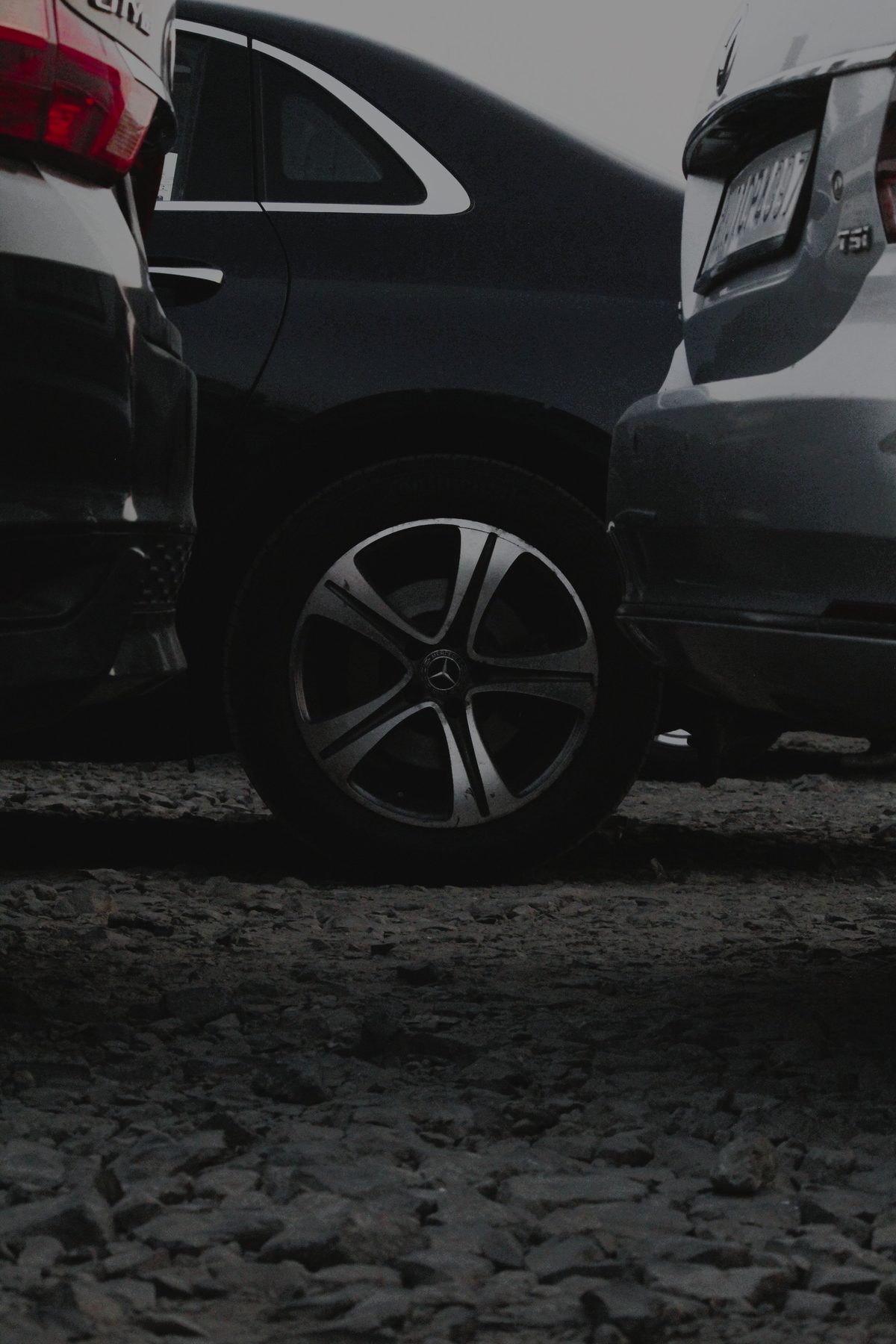 The same Mercedes-Benz wheel between parked cars in a lighter edit