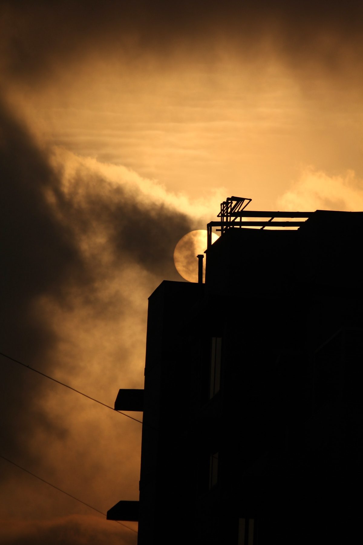 Silhouette of a rooftop against a glowing orange sunset sky